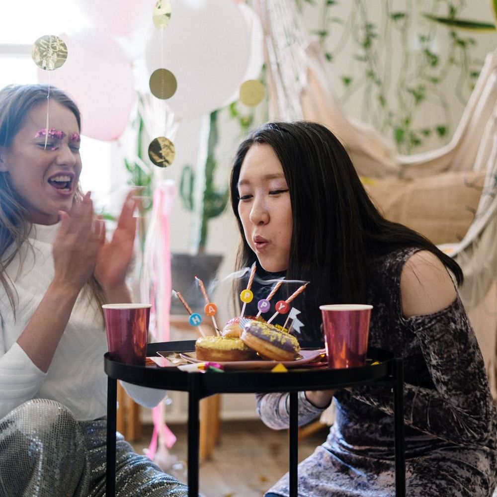 Two friends at a birthday, one blowing out the candles