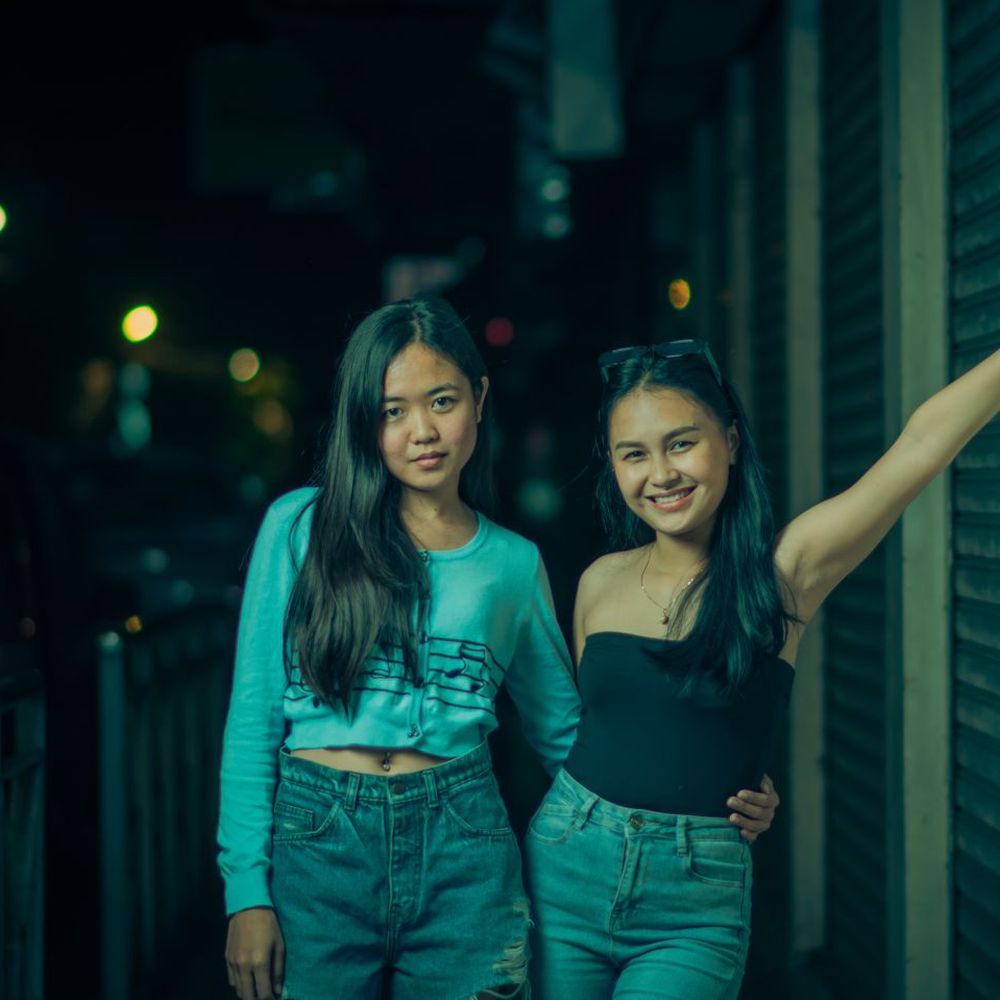 Two friends smiling on a city street at night